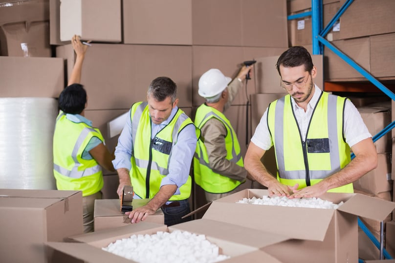 Warehouse workers in yellow vests preparing a shipment in a large warehouse